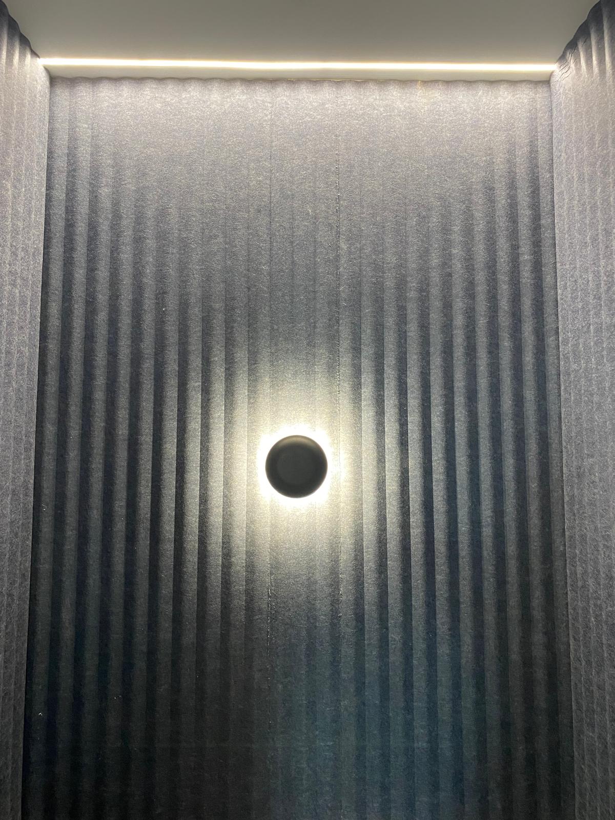 Modern circular wall light on slatted feature wall, domestic lighting design